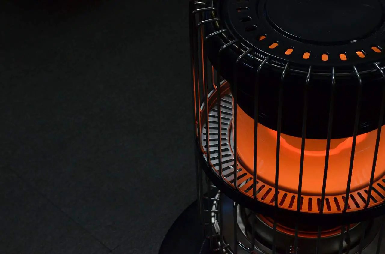 detail of a propane heater glowing orange while it warms a camping place