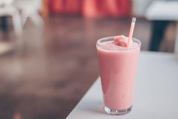 a glass of smoothie in a table with straw