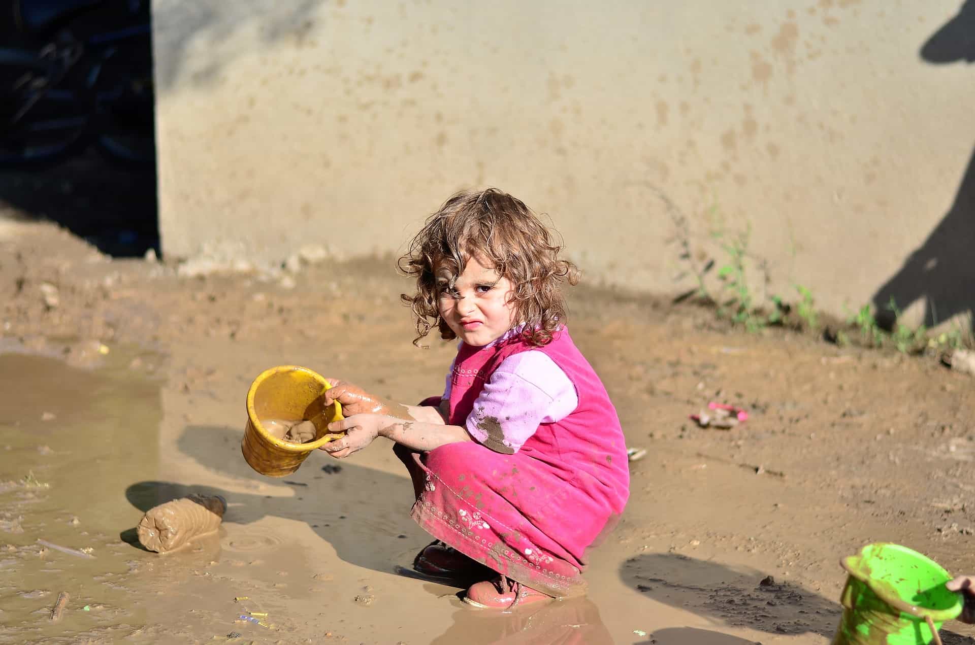 Little girl holding a toy bucket and she is playing at their backyard