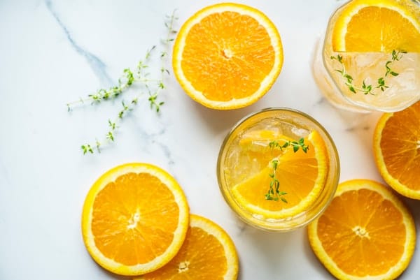 glass of lemon juice and slices of oranges